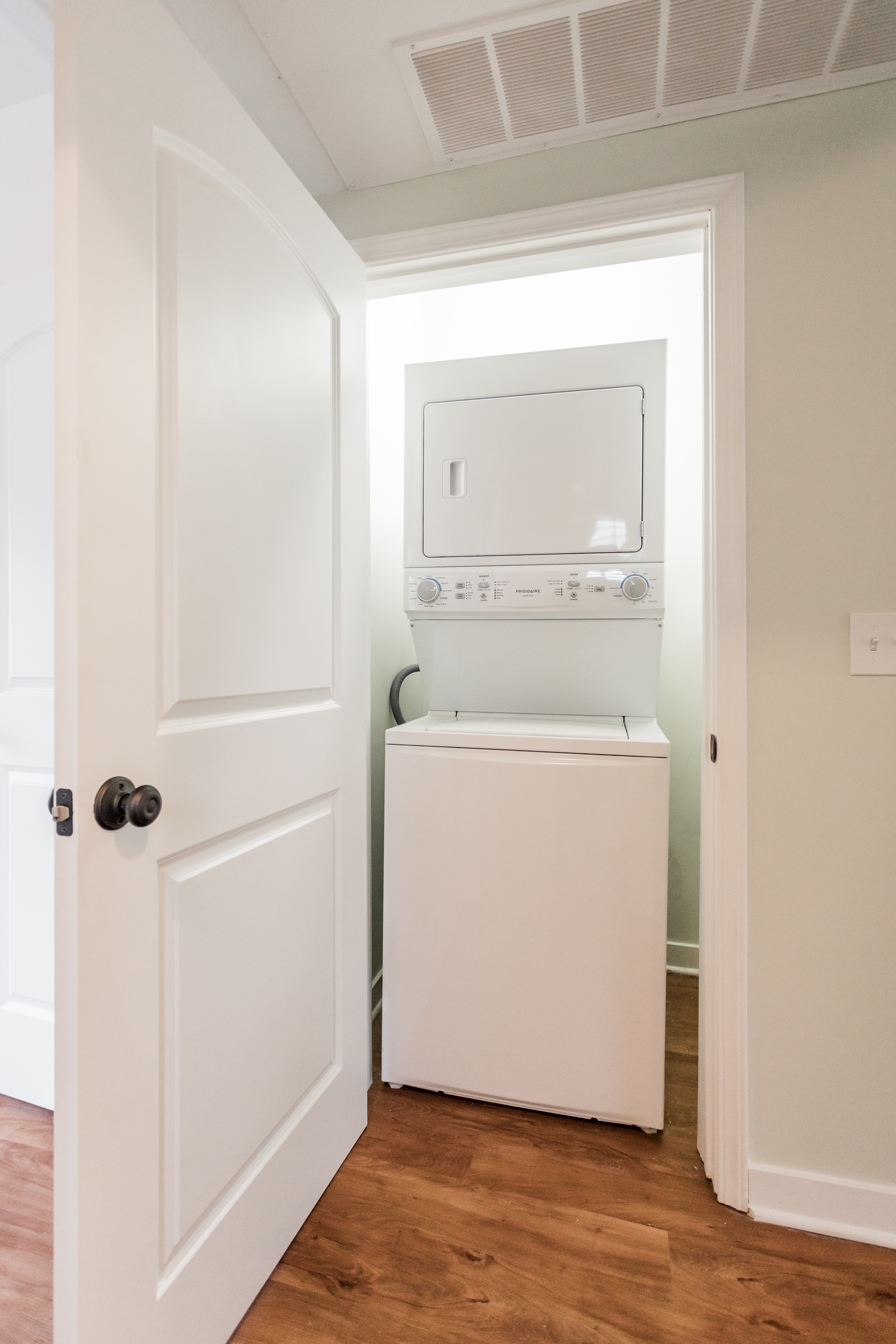 A white door is open to a small laundry room.